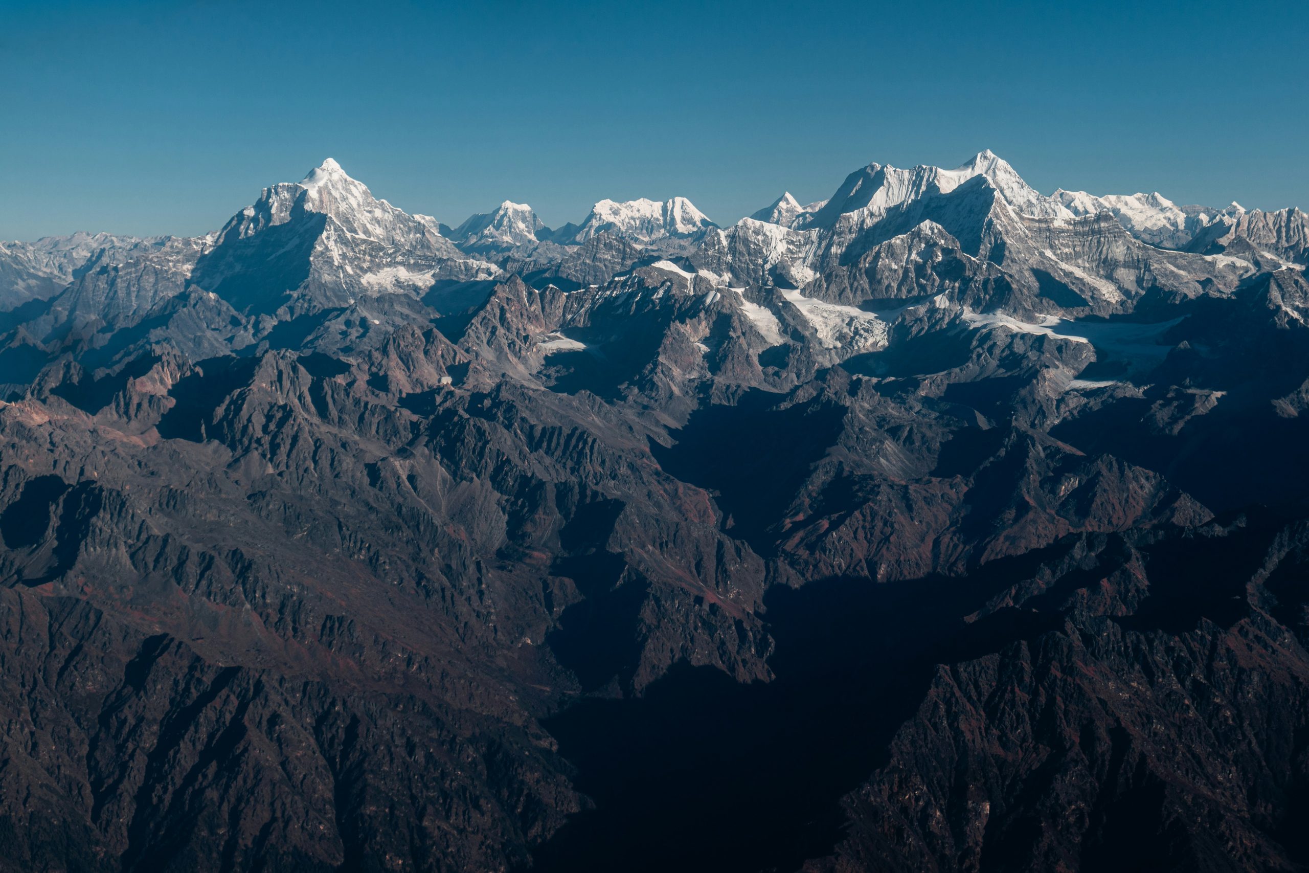 Stunning aerial view of the Himalayan mountain range from a mountain flight in Kathmandu, Nepal, with snow-capped peaks and clear blue skies.