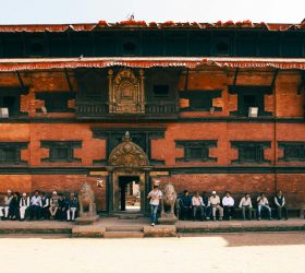 Nepali people seated in front of the Kumari Ghar (Kumari's residence) in Kathmandu, Nepal, showcasing traditional architecture and cultural heritage in the heart of the city.