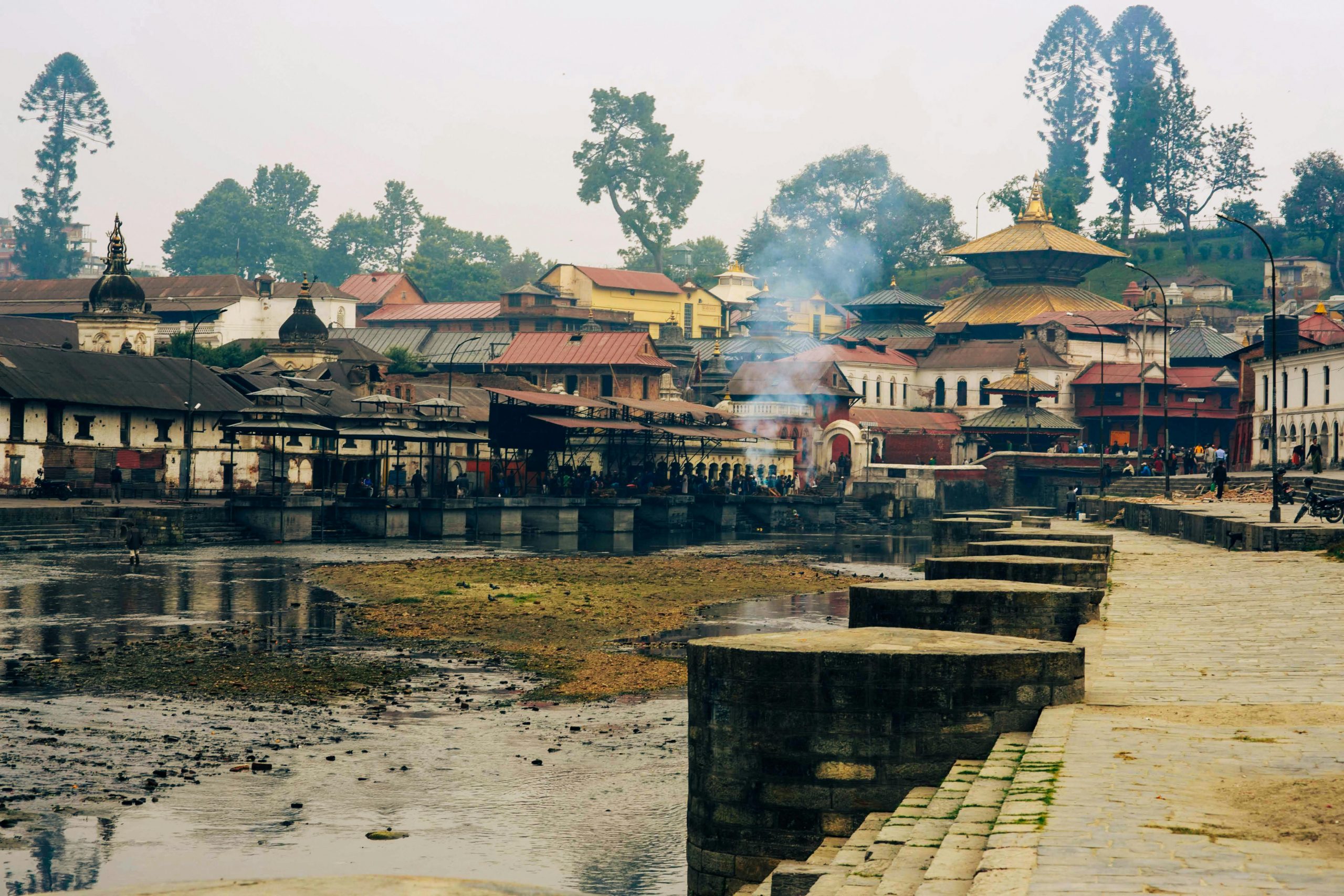 Pashupatinath Temple area, a sacred Hindu site along the Bagmati River in Kathmandu, Nepal, with devotees and cremation ghats, surrounded by intricate temples and shrines.