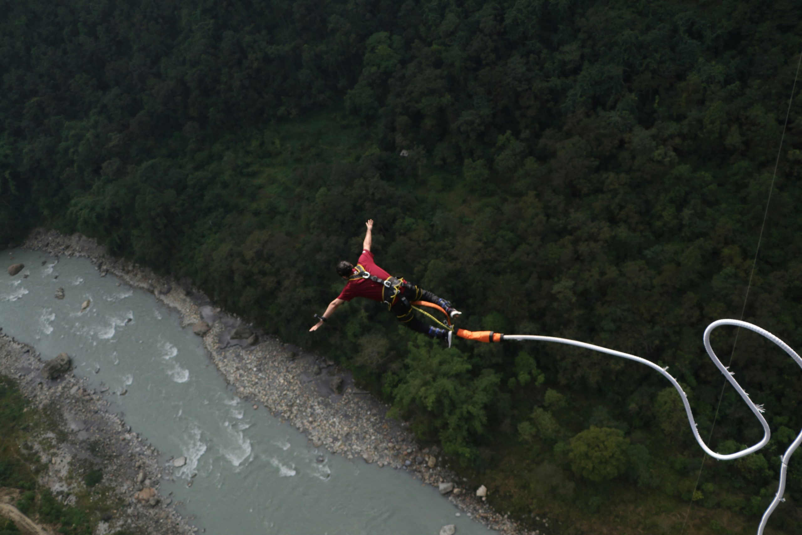 A man over the swift river during bungee jumping in Nepal