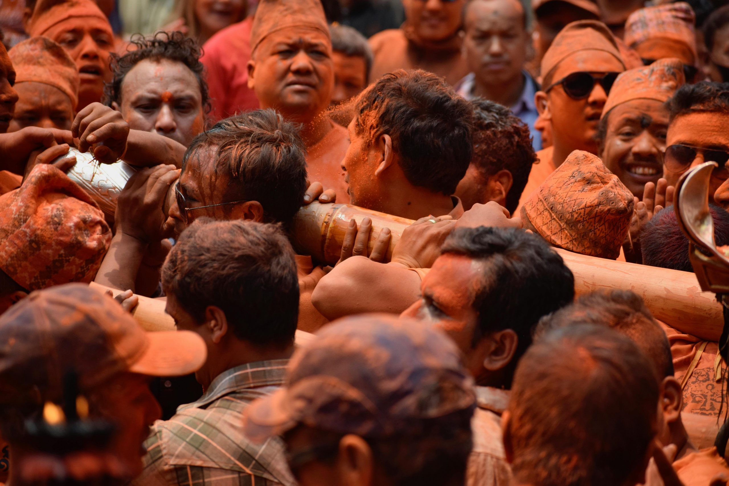 People Covered in Orange Dust Carrying a Pole During the Bisket Jatra Festival of Nepal