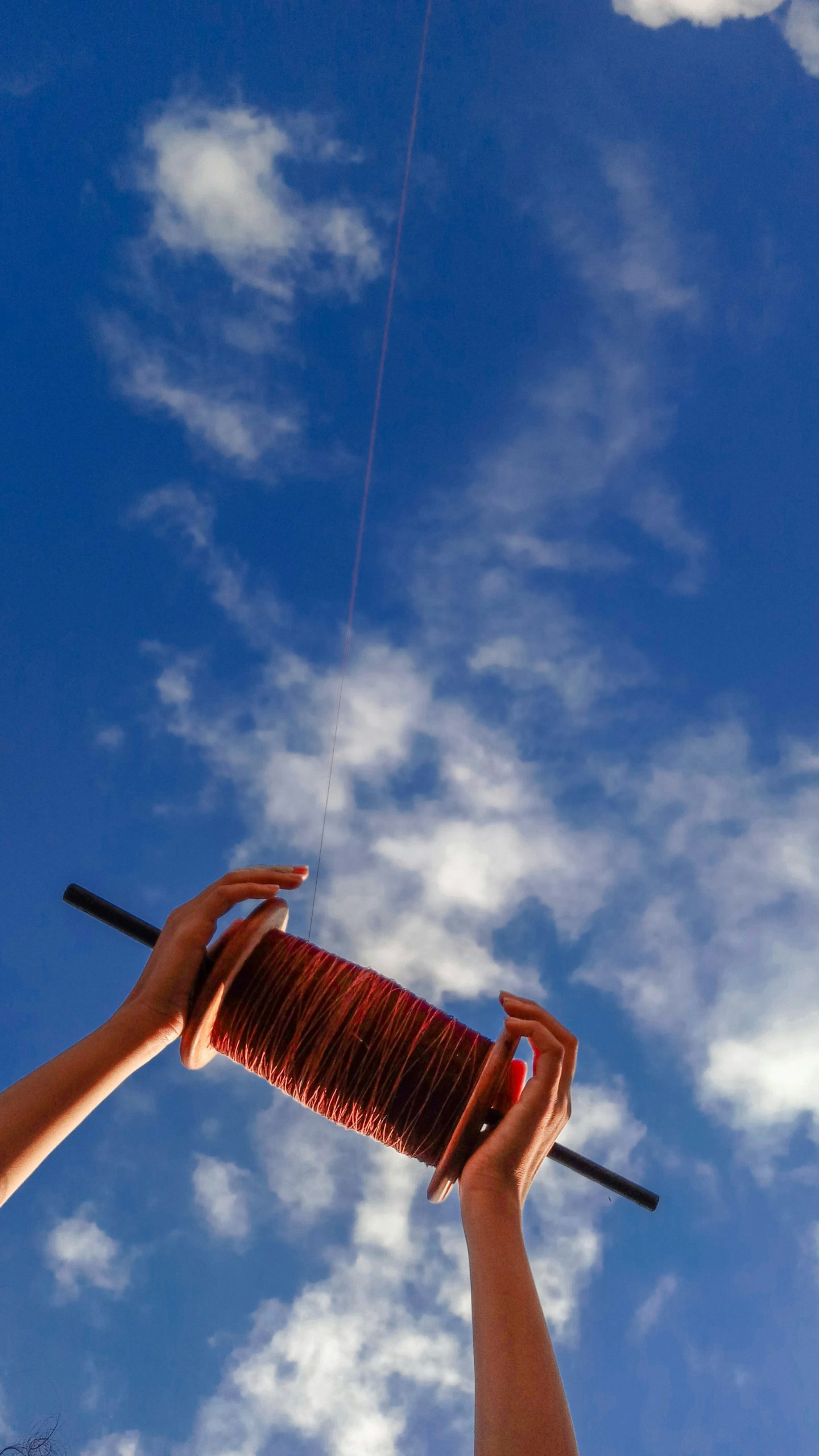 Photo of kite thread spool under cloudy sky during dashain